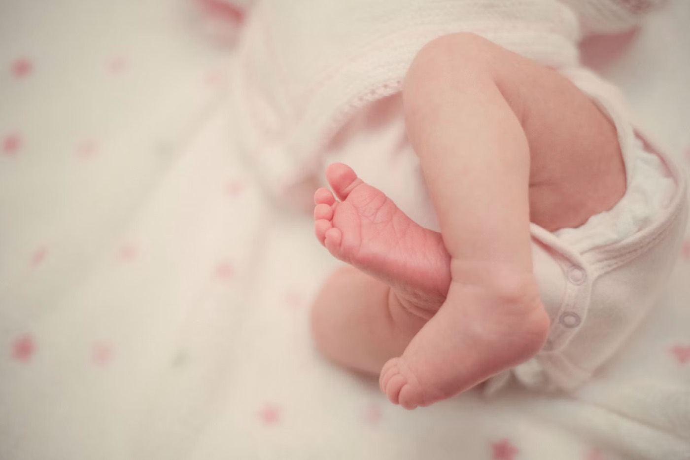 A newborn asleep, feet tucked under a blanket